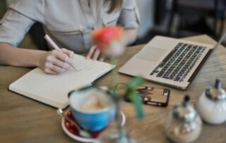 Person sitting and journaling at desk.