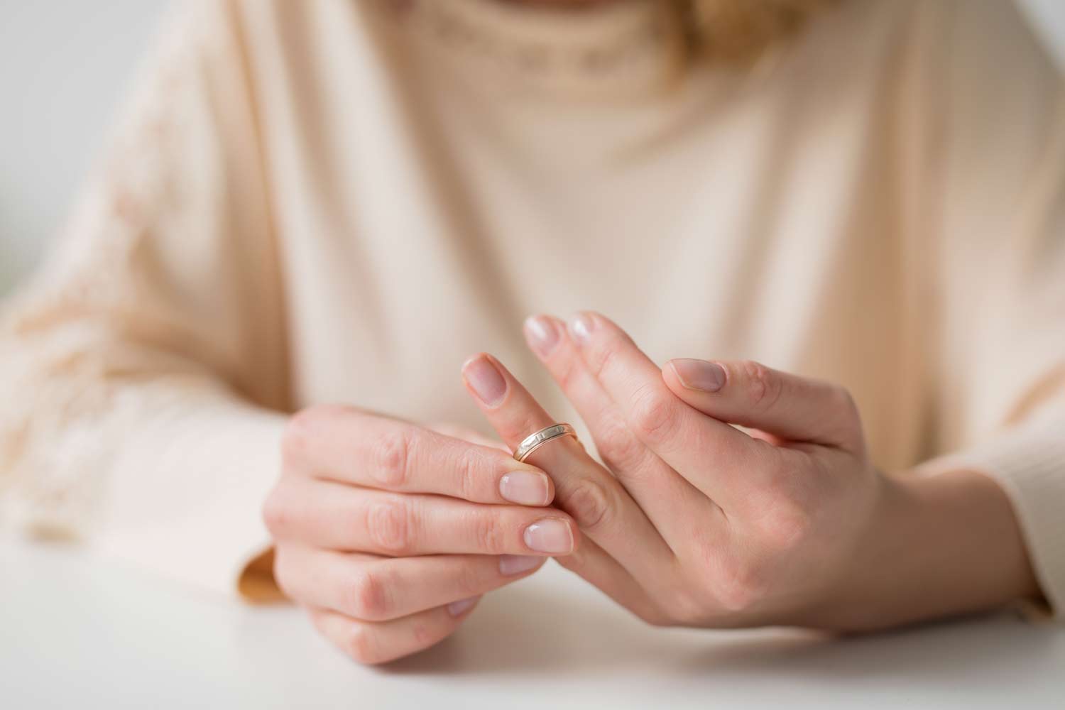 Person removing a wedding ring, representing divorce recovery, separation, and emotional healing through counseling.